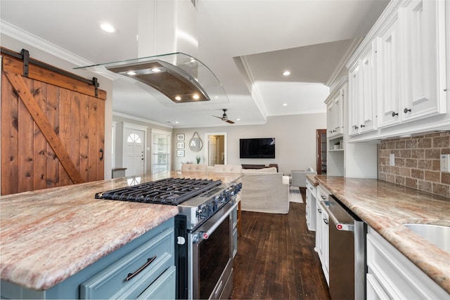 kitchen with stainless steel appliances, a barn door, blue cabinets, white cabinets, and ceiling fan