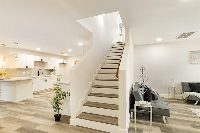 staircase featuring sink and hardwood / wood-style flooring