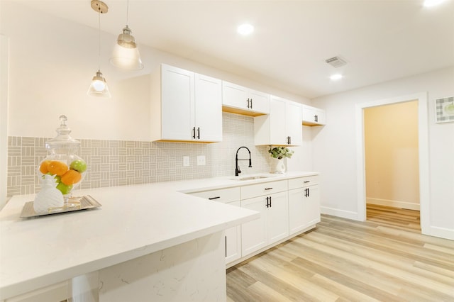 kitchen with sink, white cabinetry, tasteful backsplash, and hanging light fixtures