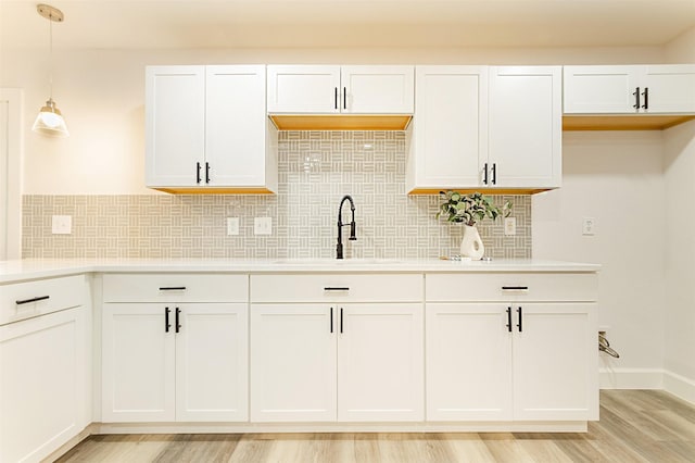 kitchen featuring sink, backsplash, white cabinets, and pendant lighting