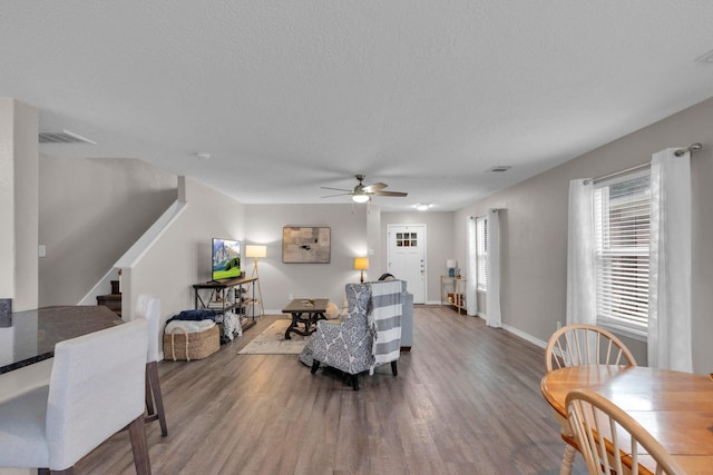 living room with a textured ceiling, ceiling fan, and dark hardwood / wood-style floors