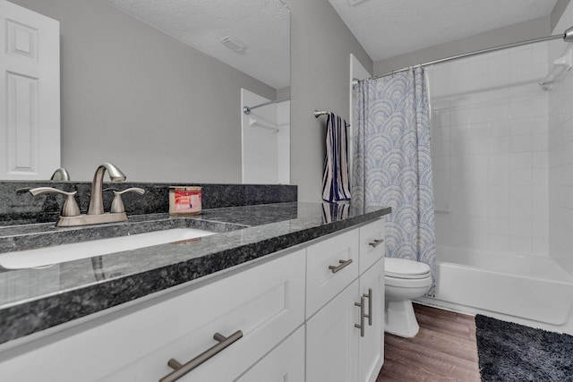 full bathroom with toilet, a textured ceiling, shower / bath combo with shower curtain, hardwood / wood-style floors, and vanity