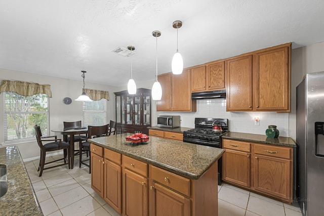 kitchen featuring tasteful backsplash, dark stone counters, a kitchen island, pendant lighting, and appliances with stainless steel finishes