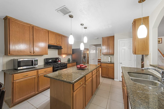 kitchen with sink, decorative light fixtures, light tile patterned floors, a kitchen island, and appliances with stainless steel finishes