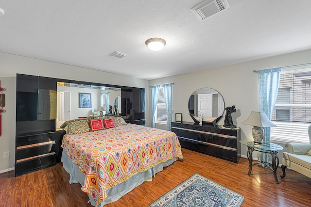 bedroom with a textured ceiling and wood-type flooring