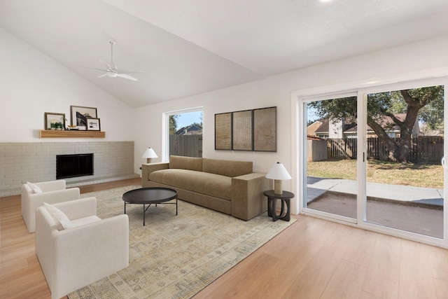 living room featuring lofted ceiling, ceiling fan, a fireplace, and light hardwood / wood-style flooring