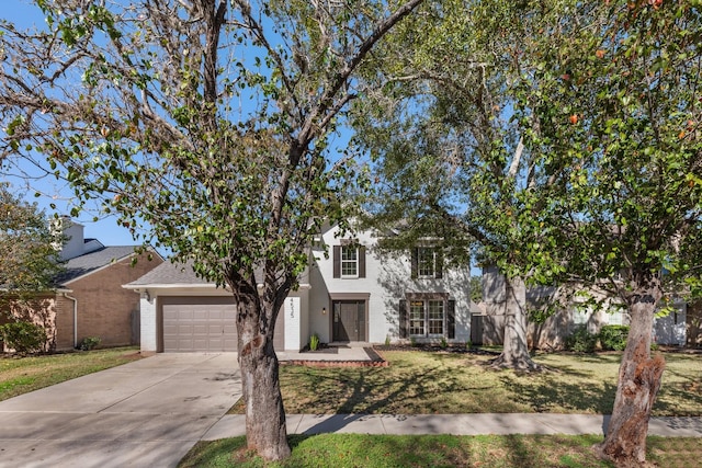 view of property hidden behind natural elements featuring a front lawn and a garage