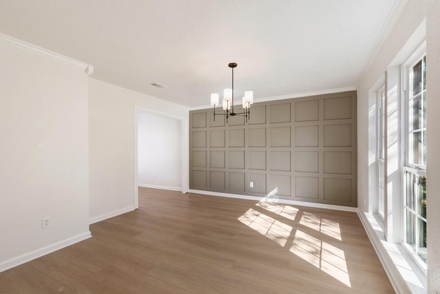 unfurnished dining area featuring a notable chandelier, ornamental molding, and light hardwood / wood-style flooring