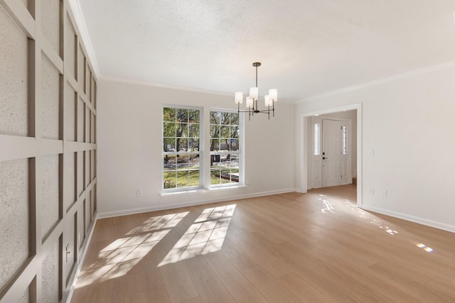 empty room featuring a notable chandelier, crown molding, and light hardwood / wood-style floors