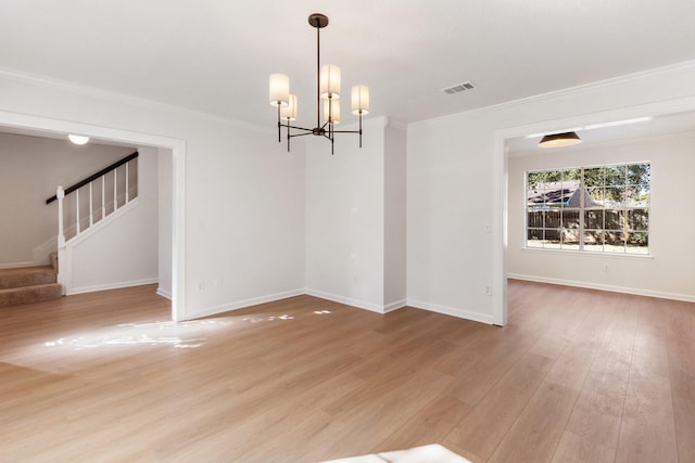 spare room featuring an inviting chandelier, ornamental molding, and hardwood / wood-style floors