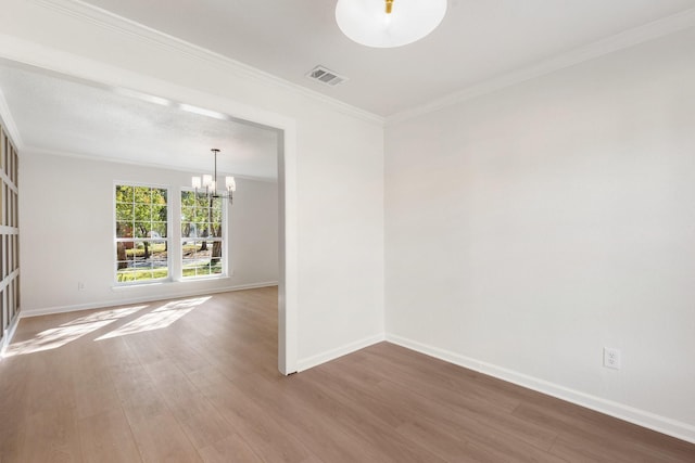 spare room featuring wood-type flooring, a notable chandelier, and ornamental molding