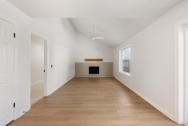 unfurnished living room featuring a brick fireplace, lofted ceiling, light hardwood / wood-style floors, and ceiling fan