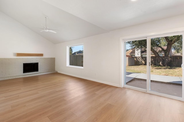 unfurnished living room featuring a brick fireplace, lofted ceiling, light hardwood / wood-style floors, and ceiling fan