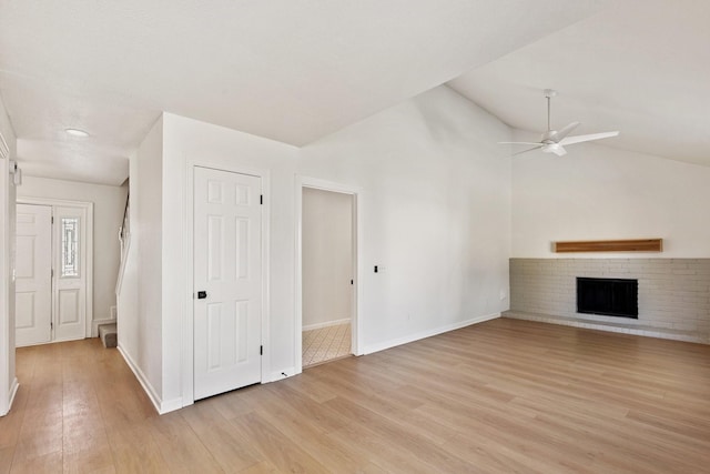 unfurnished living room featuring light hardwood / wood-style floors, lofted ceiling, ceiling fan, and a fireplace