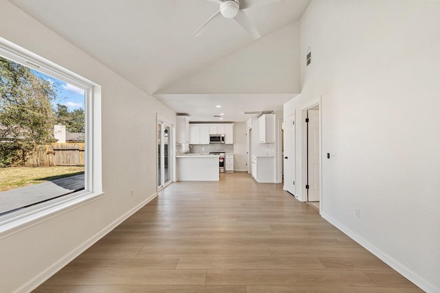 hallway with high vaulted ceiling and light hardwood / wood-style floors