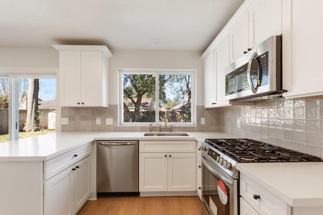 kitchen featuring decorative backsplash, a wealth of natural light, sink, appliances with stainless steel finishes, and white cabinets