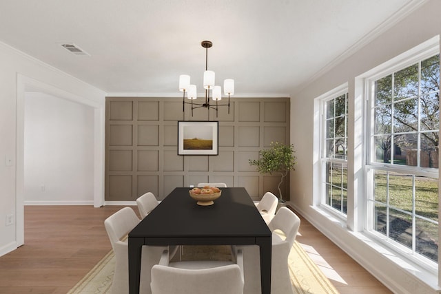 dining area with an inviting chandelier, ornamental molding, light hardwood / wood-style floors, and plenty of natural light