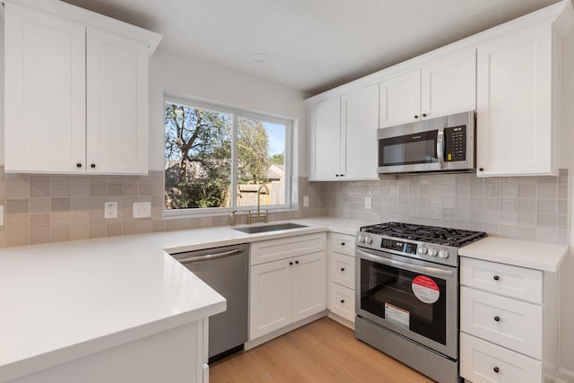 kitchen with stainless steel appliances, white cabinetry, tasteful backsplash, and sink