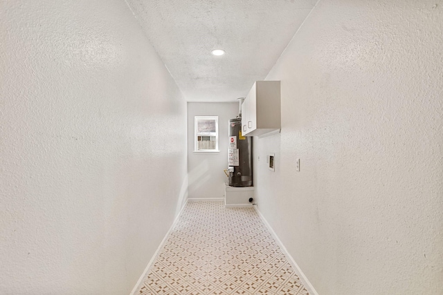 hall with water heater and a textured ceiling