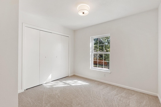 unfurnished bedroom with light carpet and a closet