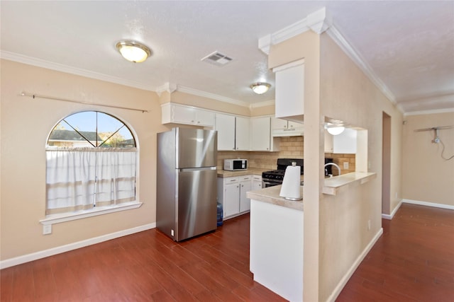 kitchen with black range with gas cooktop, stainless steel refrigerator, ornamental molding, white cabinets, and tasteful backsplash