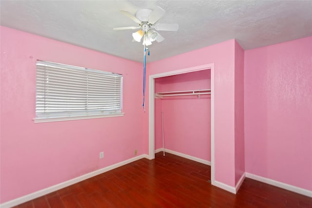 unfurnished bedroom featuring ceiling fan, dark hardwood / wood-style flooring, and a closet