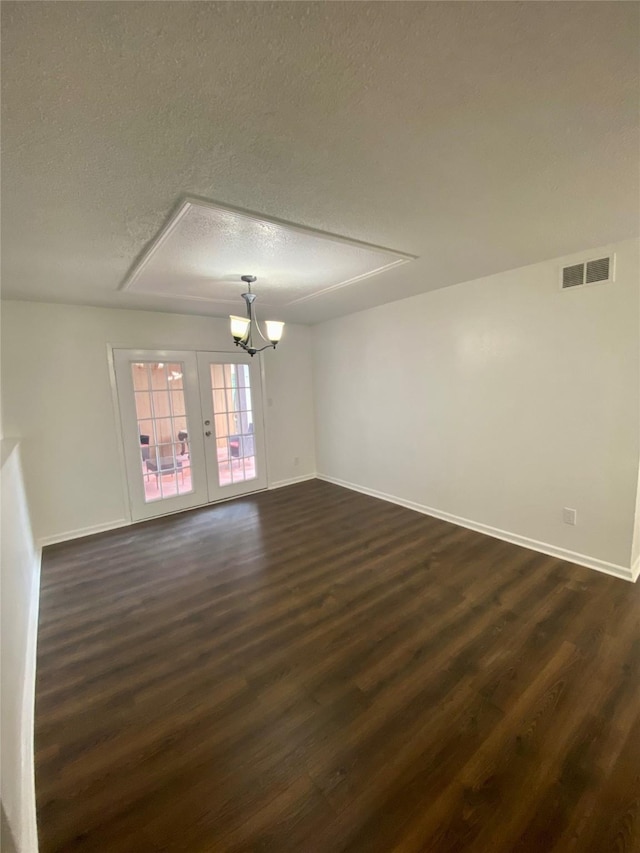 unfurnished room with a chandelier, a textured ceiling, dark hardwood / wood-style flooring, and french doors