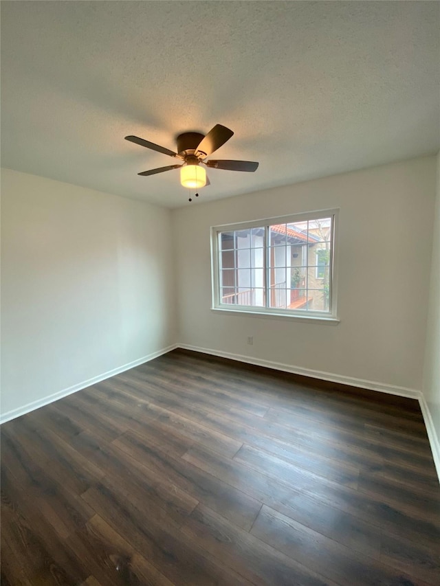 empty room featuring a textured ceiling, dark wood-type flooring, and ceiling fan