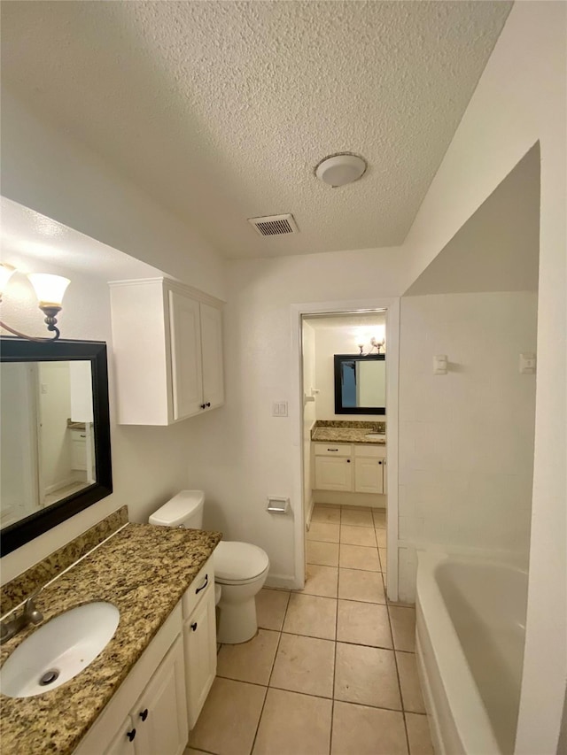 bathroom with toilet, vanity, tile patterned floors, a tub, and a textured ceiling