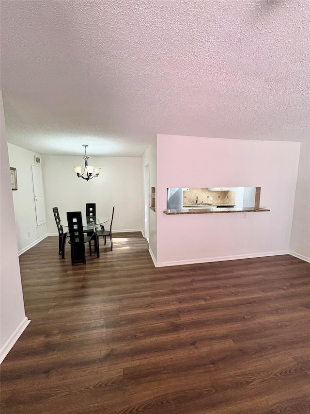 dining room with dark wood-type flooring, a textured ceiling, and a chandelier