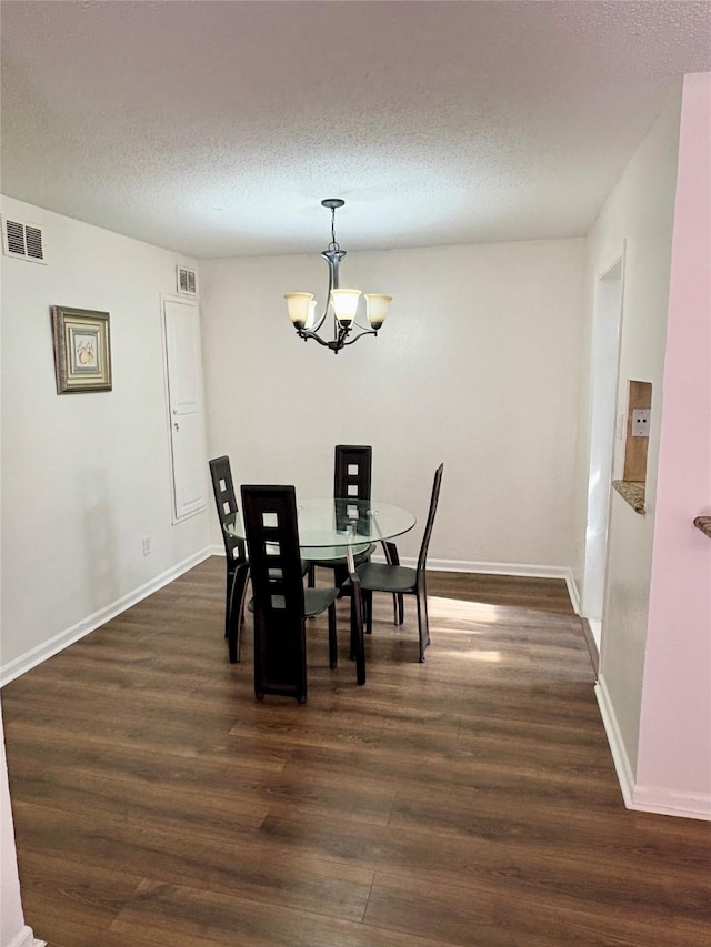 dining area featuring a textured ceiling, dark hardwood / wood-style flooring, and a notable chandelier