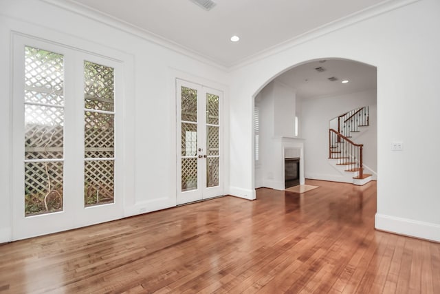 unfurnished living room featuring french doors, hardwood / wood-style floors, and ornamental molding