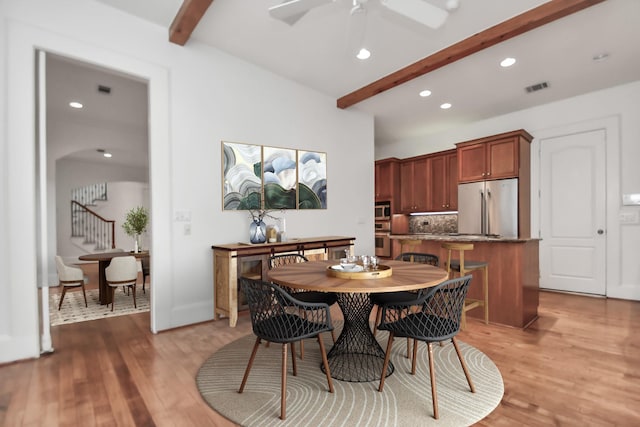 dining room with wood-type flooring, ceiling fan, and beamed ceiling