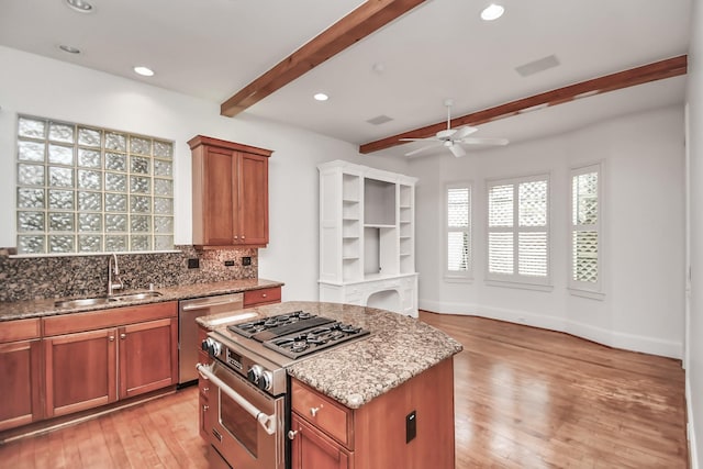 kitchen featuring sink, a center island, stainless steel range with gas stovetop, dishwashing machine, and beam ceiling