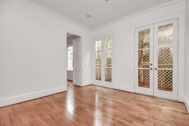 unfurnished room featuring ornamental molding, light wood-type flooring, and french doors