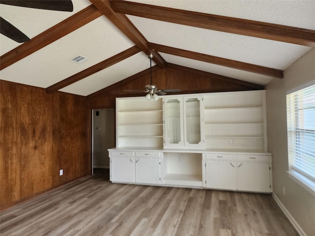 unfurnished living room featuring a textured ceiling, vaulted ceiling with beams, ceiling fan, light hardwood / wood-style floors, and built in shelves