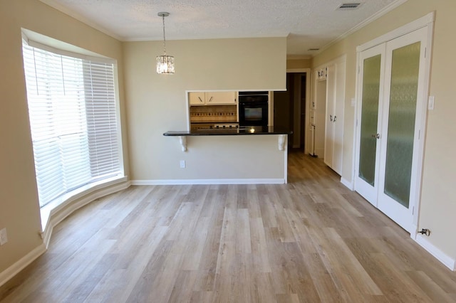 unfurnished living room featuring a textured ceiling, light hardwood / wood-style flooring, crown molding, and a chandelier