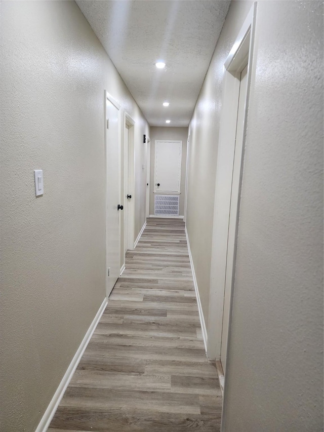 corridor featuring a textured ceiling and light wood-type flooring