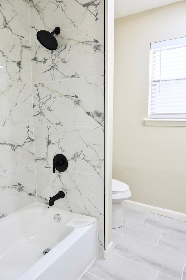 bathroom featuring tile patterned floors, tiled shower / bath combo, and toilet