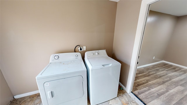 clothes washing area with independent washer and dryer and light wood-type flooring