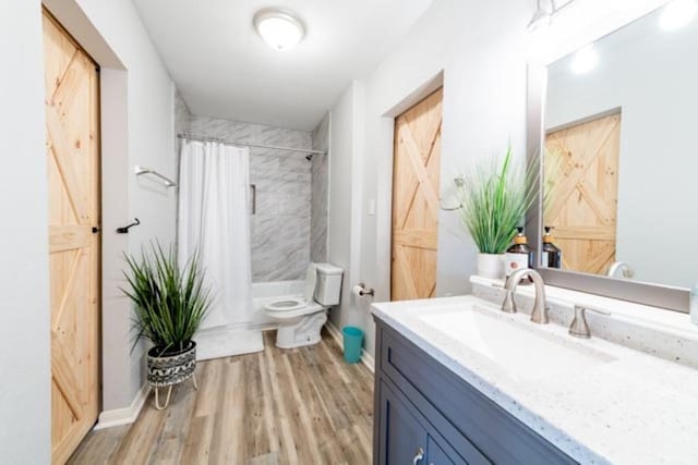 bathroom featuring toilet, shower / tub combo, wood finished floors, vanity, and baseboards