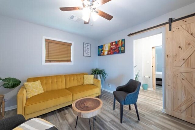 living room with ceiling fan, hardwood / wood-style floors, and a barn door