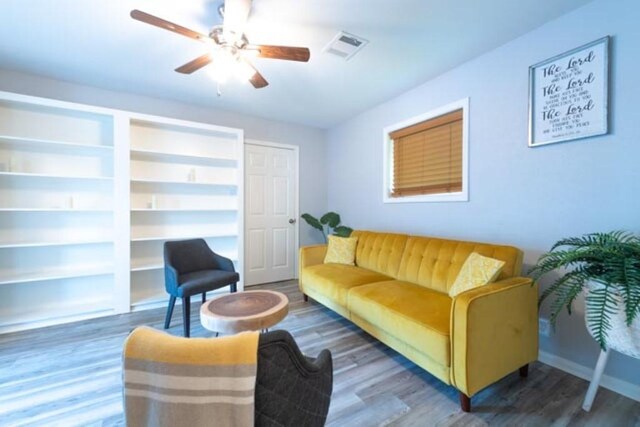 living room with dark wood-type flooring, built in features, and ceiling fan