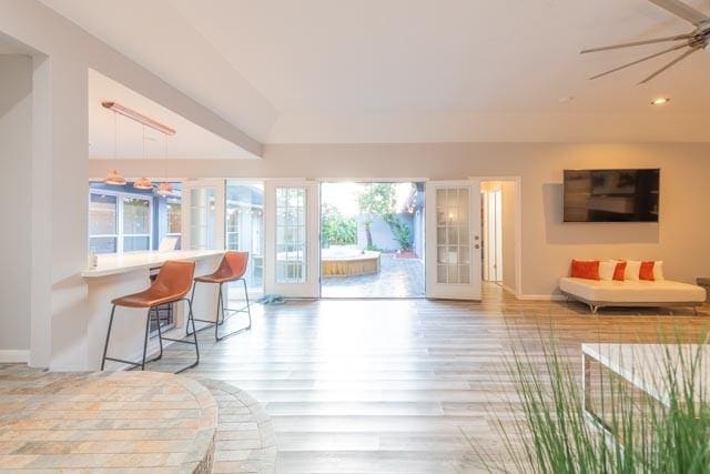 living room with a ceiling fan, light wood-type flooring, and baseboards