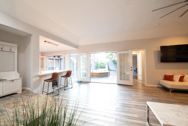 living room with french doors, light wood-type flooring, and baseboards