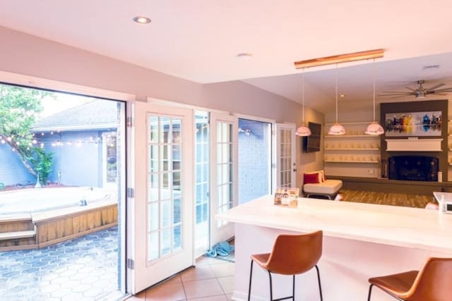 kitchen featuring a fireplace, ceiling fan, hanging light fixtures, and a breakfast bar area