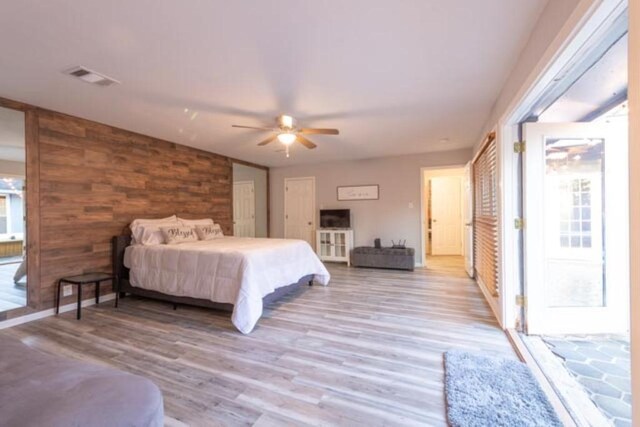 bedroom featuring wooden walls, ceiling fan, and light hardwood / wood-style floors