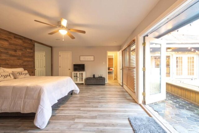 bedroom with hardwood / wood-style floors, wood walls, and ceiling fan