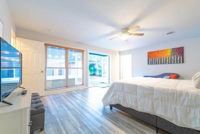 bedroom featuring ceiling fan, wood finished floors, visible vents, and access to exterior