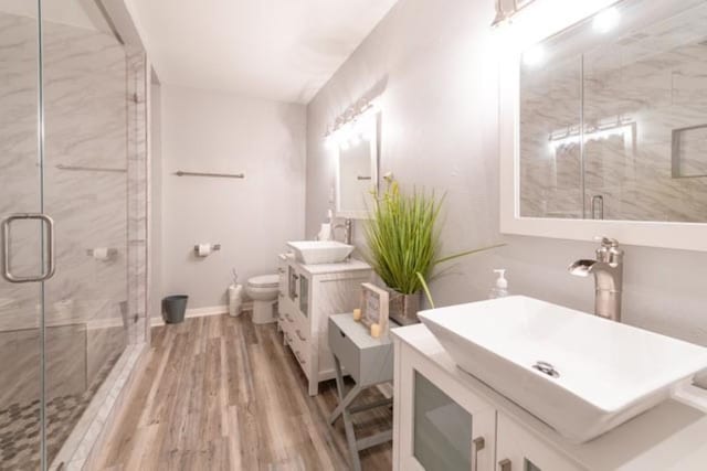 bathroom featuring a marble finish shower, two vanities, and a sink